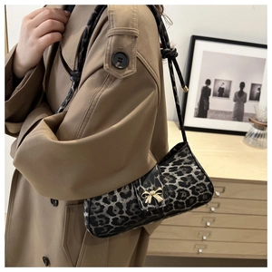 Leopard print baguette bag with gold bow buckle worn over a stylish khaki trench coat