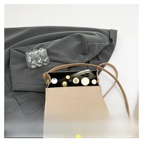 Detail view of the open beige crocodile pattern bag interior with phone and cosmetics