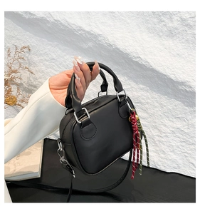 Detail of black leather mini bowling bag with unique colorful braided rope charm