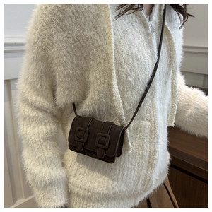 Close-up of brown croc-embossed micro crossbody bag worn on a white knit sweater