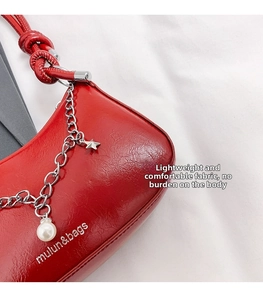 Detail of red glossy shoulder bag with silver chain, star pendant and pearl accent