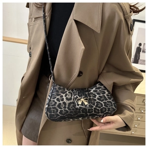 Detail of leopard print crossbody bag with golden bow buckle on a camel trench coat