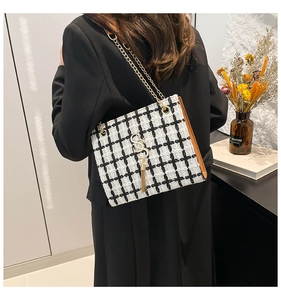 Close-up of black and white tweed shoulder bag with gold chain and tassel detail