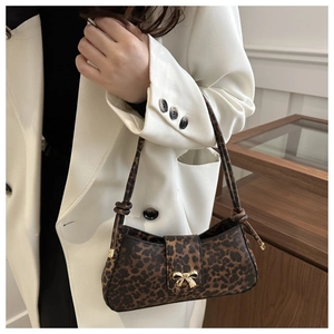 Detail of leopard print underarm bag with gold bow clasp on white blazer outfit