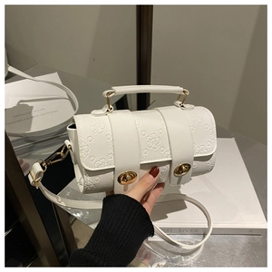Detail of white Boston bag featuring embossed floral patterns and gold twist-lock closures