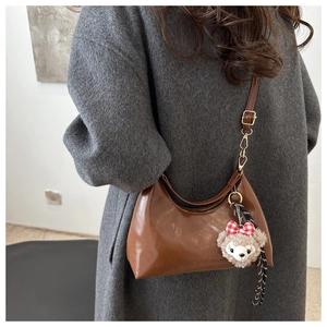 Detail of vintage oil-wax leather crescent bag with bear charm and adjustable strap
