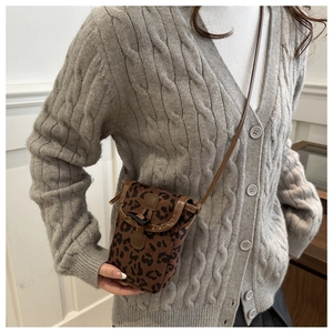 Detail of the leopard print crossbody bag with brown leather trim on a grey sweater