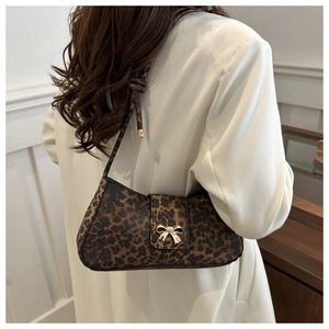 Detail of leopard print hobo bag with a golden bow buckle and slim shoulder strap