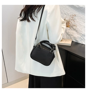 Close-up of minimalist black leather bowling bag with silver hardware on a model