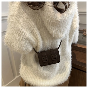 Detail of a brown croc-embossed mini crossbody bag styled on a white fuzzy sweater