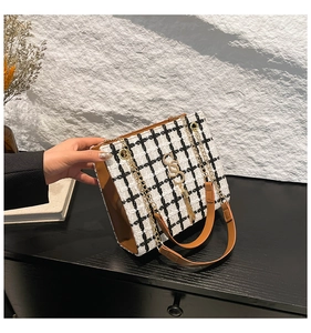 Detail of tweed check shoulder bag with leather trim, metal chain and tassel charm