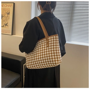 Detail of checkered tote bag showing tweed texture and brown leather strap with gold rivets