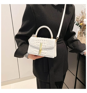 Detail of white crocodile pattern handbag with gold bamboo twist lock on black coat