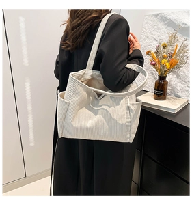 Side view of a large cream corduroy tote bag with side pockets on a female model