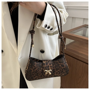 Leopard print crossbody bag with gold bow buckle styled on a white blazer outfit
