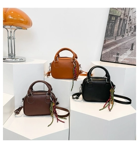 Three mini leather bowling bags in brown and black on display with woven tassels