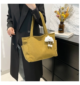 Detail of mustard yellow corduroy tote bag with side pocket and cloud plush pendant charm
