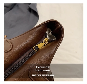 Close-up of golden zipper hardware on brown litchi pattern leather tote bag