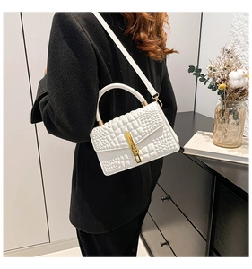 Rear view of a model wearing a white croc-effect crossbody bag with gold metal lock