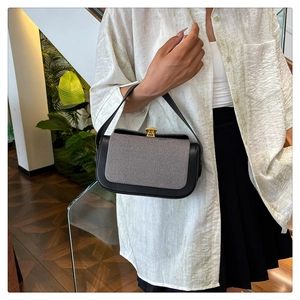 Détail du rabat en sergé gris et cuir noir avec fermoir doré sur le sac à main
