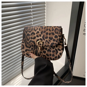 Detail of leopard print crossbody bag featuring a golden horseshoe clasp and flap design