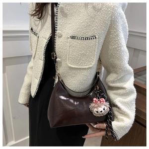 Detail of dark brown glossy oil wax leather shoulder bag with plush bear charm