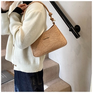 Detail of light khaki shoulder bag featuring lace floral texture and decorative knotted strap