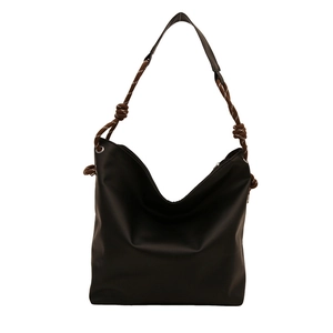 Minimalist black tote bag with brown braided rope handle and knot detail for daily commute