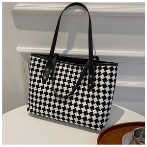 Detail of checkered tote bag with gold studs and thin black straps on a table