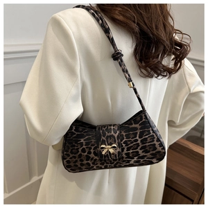 Close-up of leopard print baguette bag with golden bow hardware and slim shoulder strap