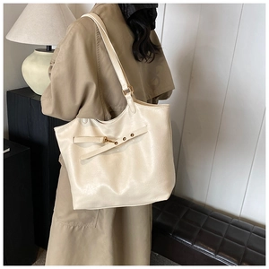 Close-up of off-white leather tote bag with decorative straps and metal buckle detail
