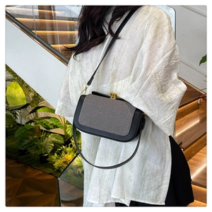 Détail d'un sac à bandoulière rétro avec rabat en tissu gris et fermoir doré chic