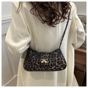 Leopard print underarm shoulder bag with golden bow buckle on a beige wool coat