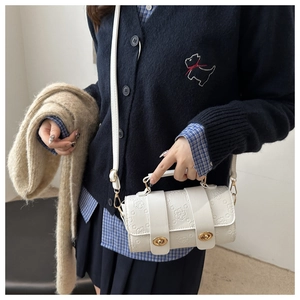 Detail of white Boston bag featuring floral embossed texture and golden hardware accents