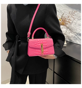 Hot pink crocodile textured handbag with gold hardware worn over a black wool coat