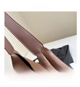 Detailed macro view of wide caramel brown leather shoulder strap with neat stitching