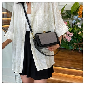 Détail du rabat gris rayé d'un sac bandoulière noir avec boucle dorée vintage