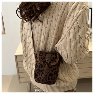 Détail du petit sac à imprimé léopard porté avec un pull en maille beige chaud