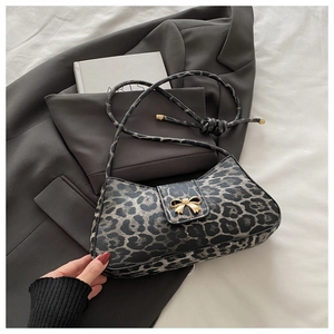 Close-up of leopard print shoulder bag with gold bow ornament on a grey blazer