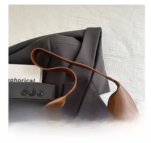 Close-up of brown leather tote bag texture paired with a grey blazer and book