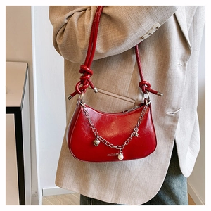 Detail of red crescent hobo bag with silver chain charms and knotted rope strap
