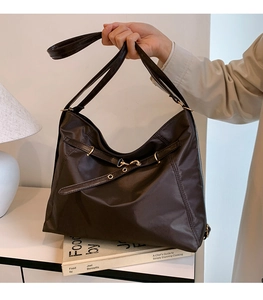 Detail of a chocolate brown nylon tote bag with decorative straps and golden hardware