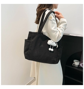 Detail of black corduroy tote bag texture with cute cloud plush charm and side pocket