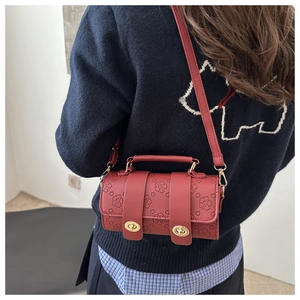 Detail showing vintage red leather barrel bag with floral embossing and gold metal twists