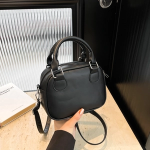 Chic black vintage bowling bag with dual handles and detachable strap in a minimalist style