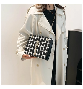 Close-up of black and white checkered tweed shoulder bag with gold chain and S-shaped pendant