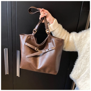 Detailed view of dark brown tote bag with cross straps and lychee texture