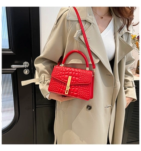 Detail of red crocodile texture handbag with gold metal lock on beige trench coat