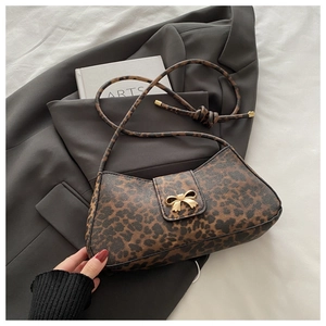 Detail of leopard print handbag featuring a gold bow buckle and knotted shoulder strap