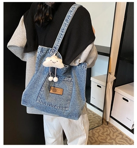 Détail du grand sac cabas en jean bleu avec étiquette en cuir et peluche nuage blanc